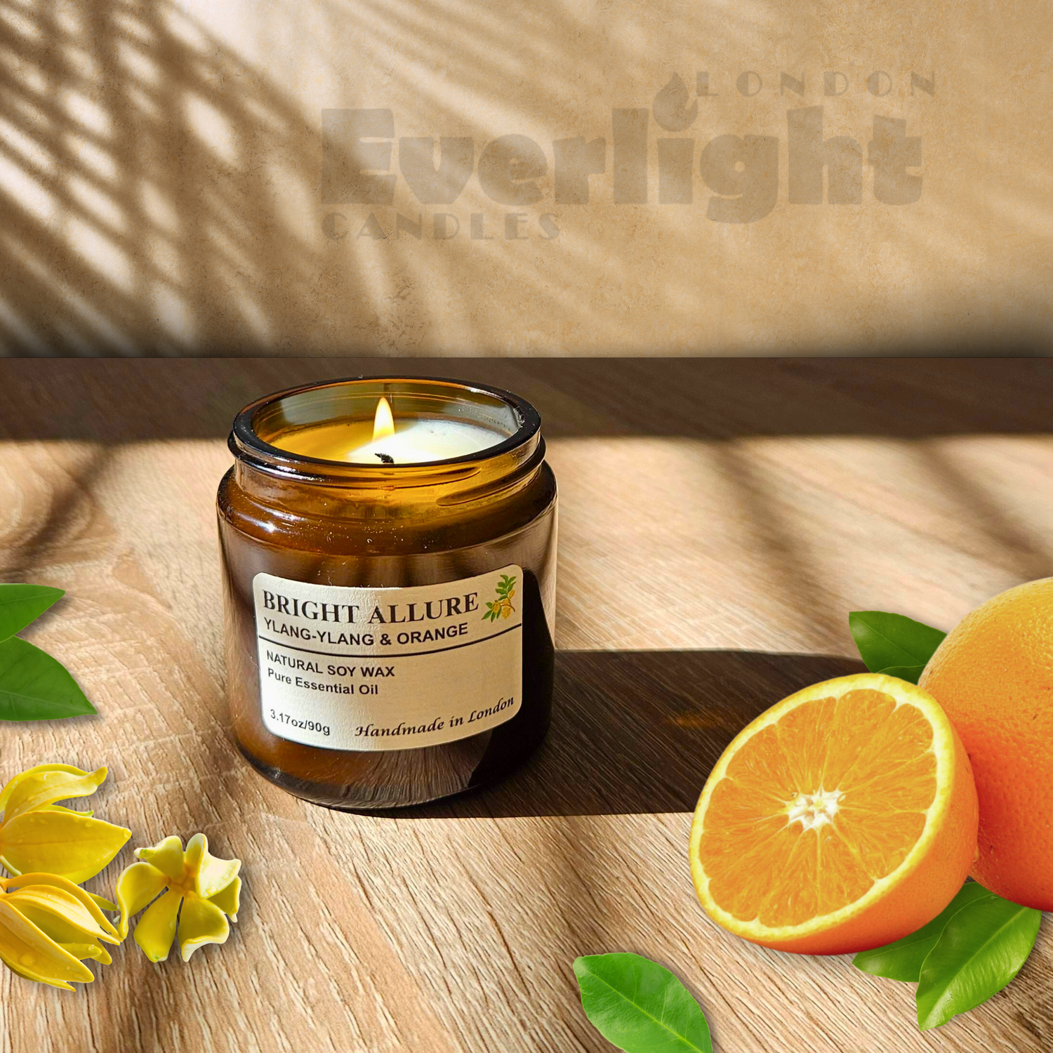 Amber small candle jar burning with oranges and Ylang Ylang flowers in a beige wooden background